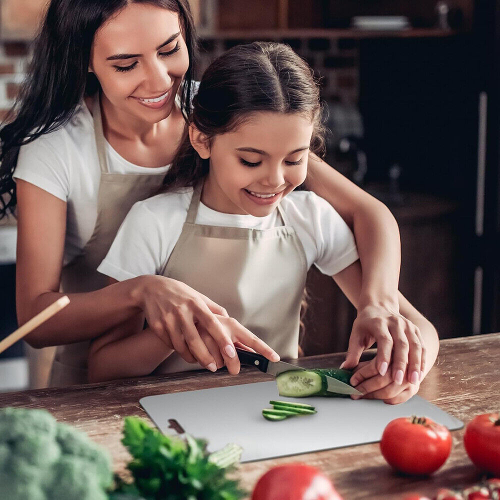 Woman and young girl in aprons preparing vegetables together in a kitchen.