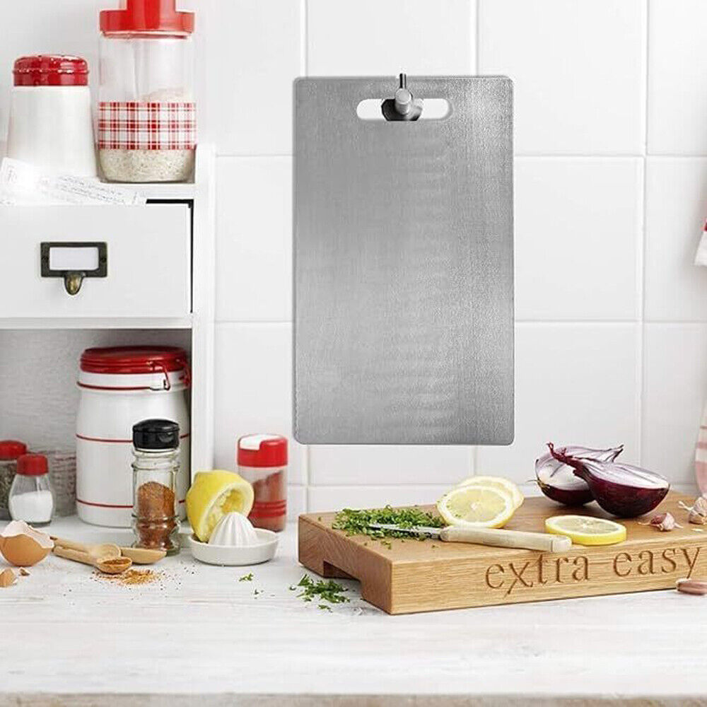 Gray cutting board on a kitchen counter with various kitchen items.

