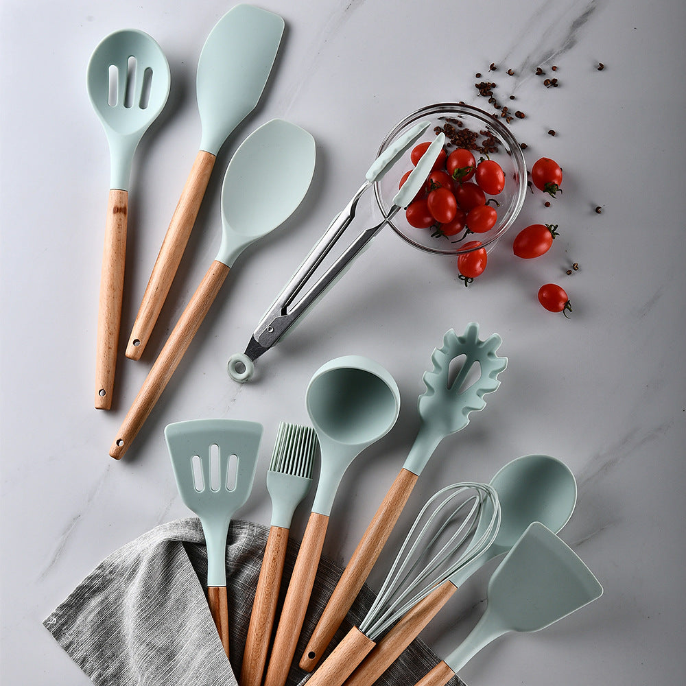 Set of kitchen utensils with wooden handles on a marble surface with tomatoes.