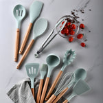 Set of kitchen utensils with wooden handles on a marble surface with tomatoes.