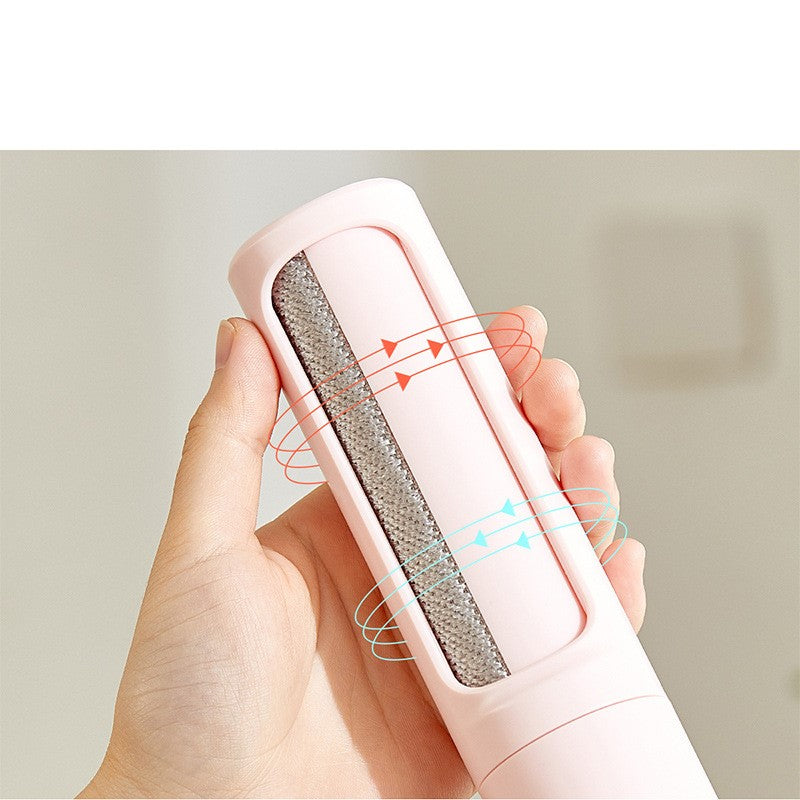 Pink self-cleaning pet hair remover brush held in hand, designed to remove pet fur, lint, and hair from clothing, furniture, and fabric surfaces.