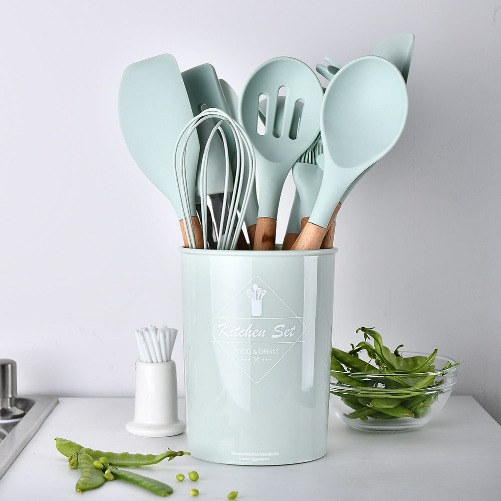 Set of kitchen utensils in a light blue holder on a white countertop.