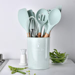 Set of kitchen utensils in a light blue holder on a white countertop.