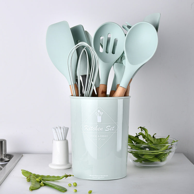 Set of kitchen utensils in a light blue holder on a white countertop.